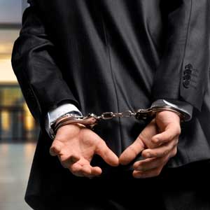 Man in business suit with hands cuffed behind back